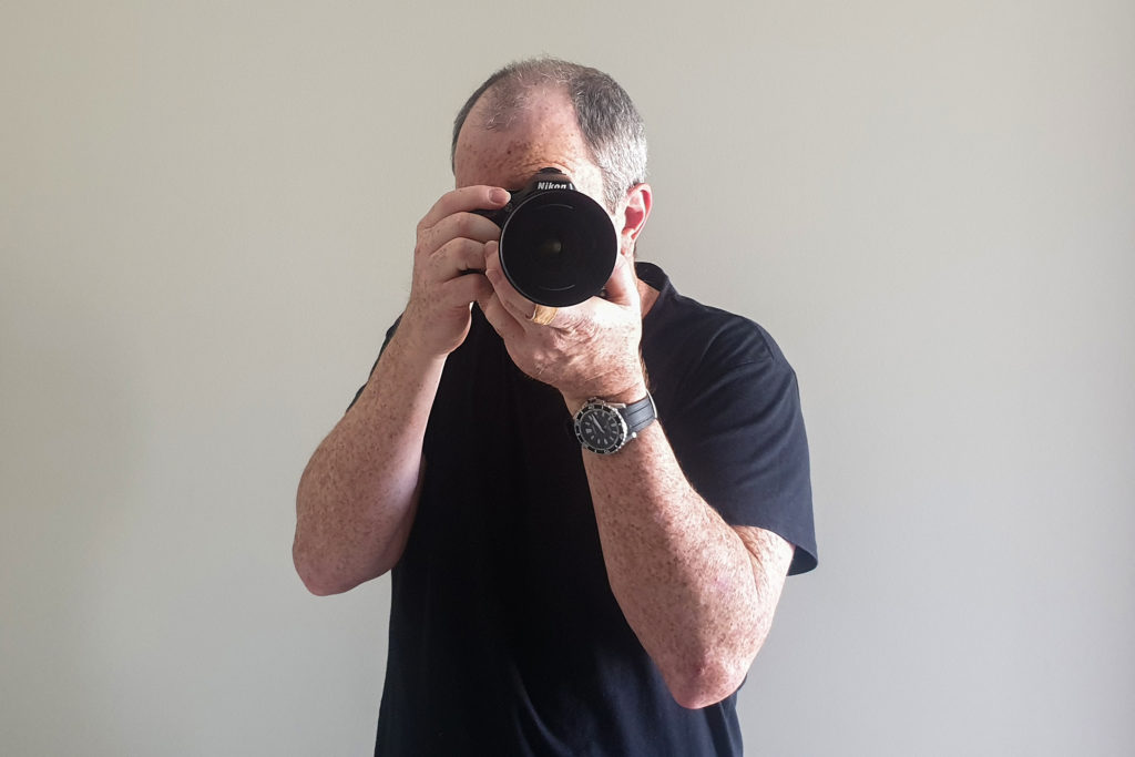 photograhy tips for beginners - A man holding a dslr camera facing to the front