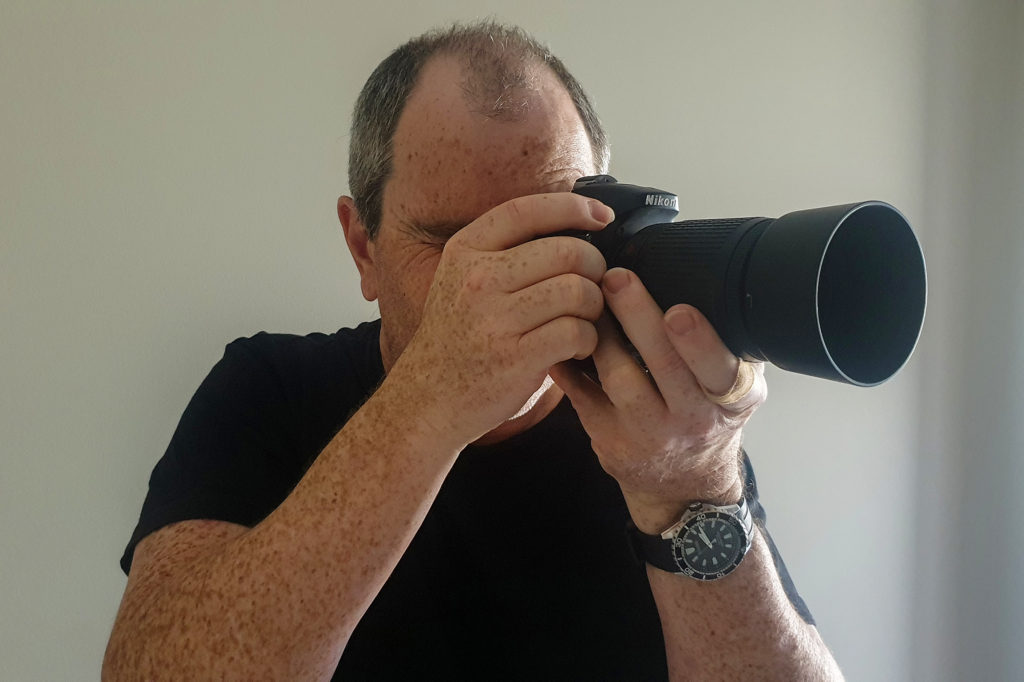 man holding a dslr camera viewed from his right side
