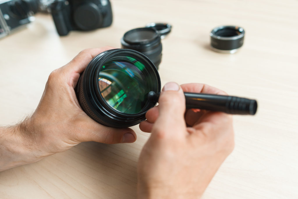 man cleaning a camera lens with a brush