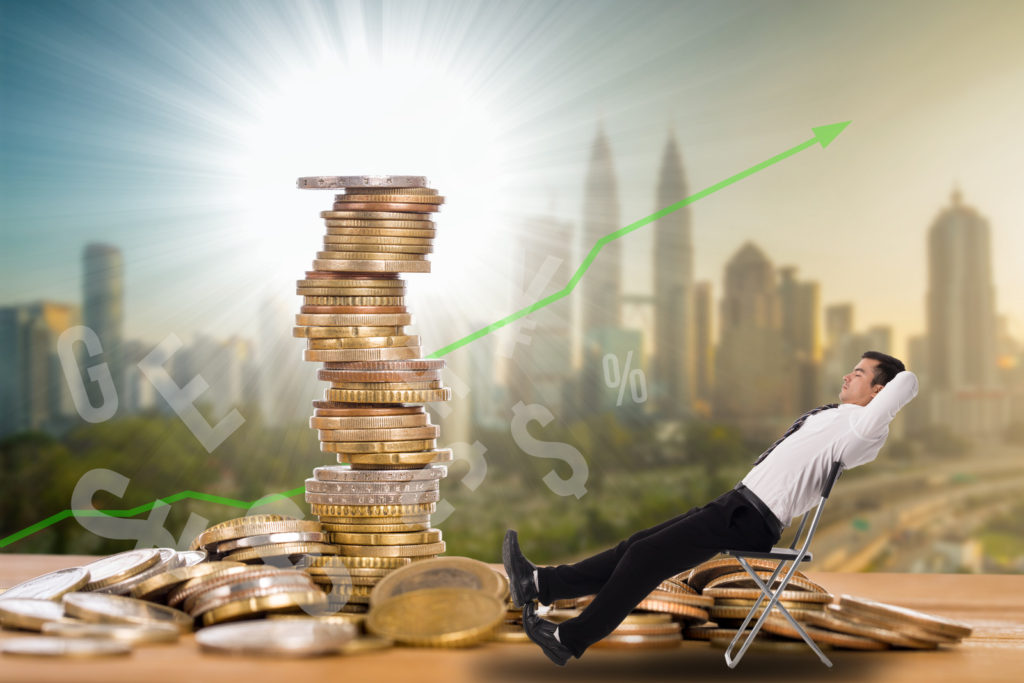 image depicting passive income with a businessman relaxing on a chair next to a pile of money
