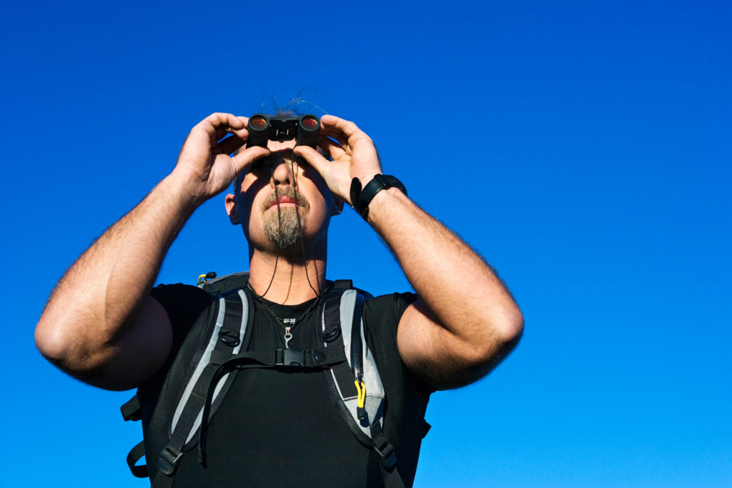 how to make more time for photography - man looking through binoculars
