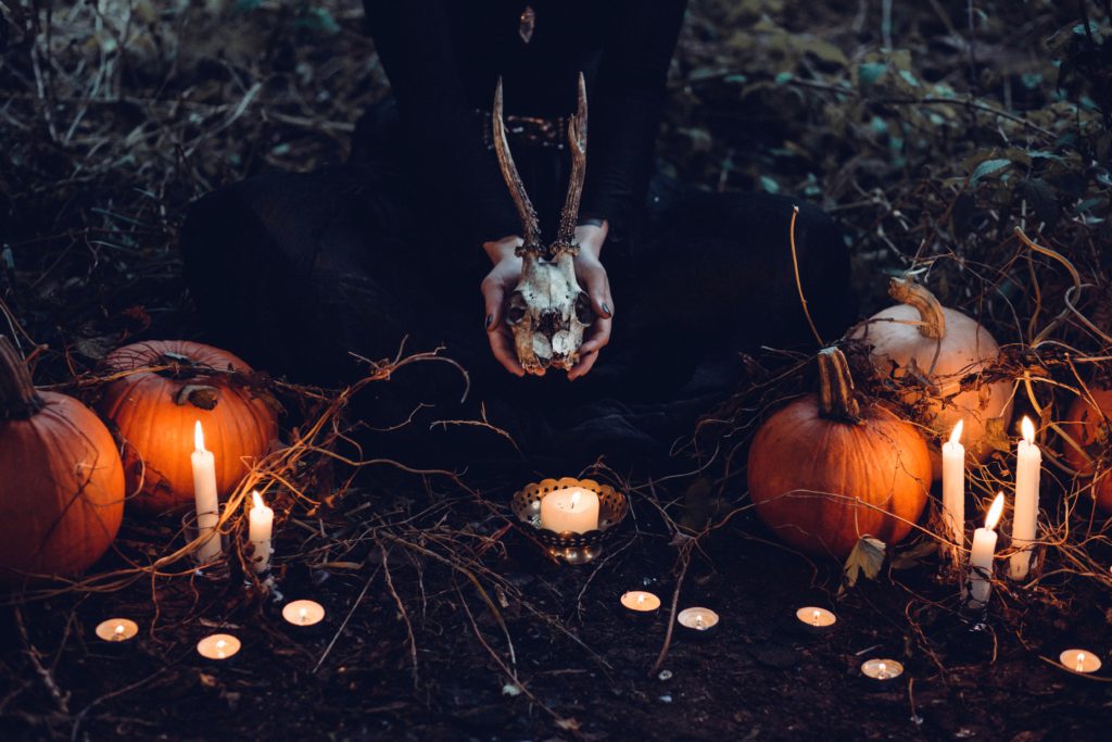 the best time of the day to take photos - image of a woman sitting between pumpkins and candles,  holding a skull
