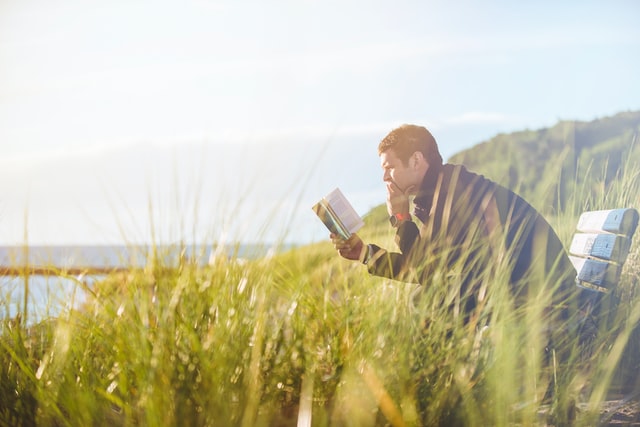 5 ways to improve business - man reading a book on a bench outside
