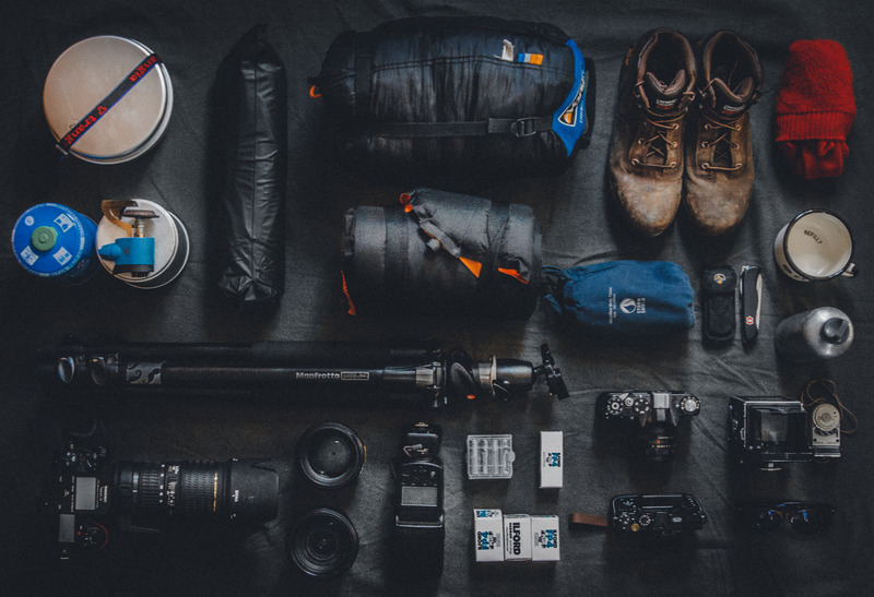 make money with photography as a beginner - camera equipment and hiking gear laid out on a grey blanket