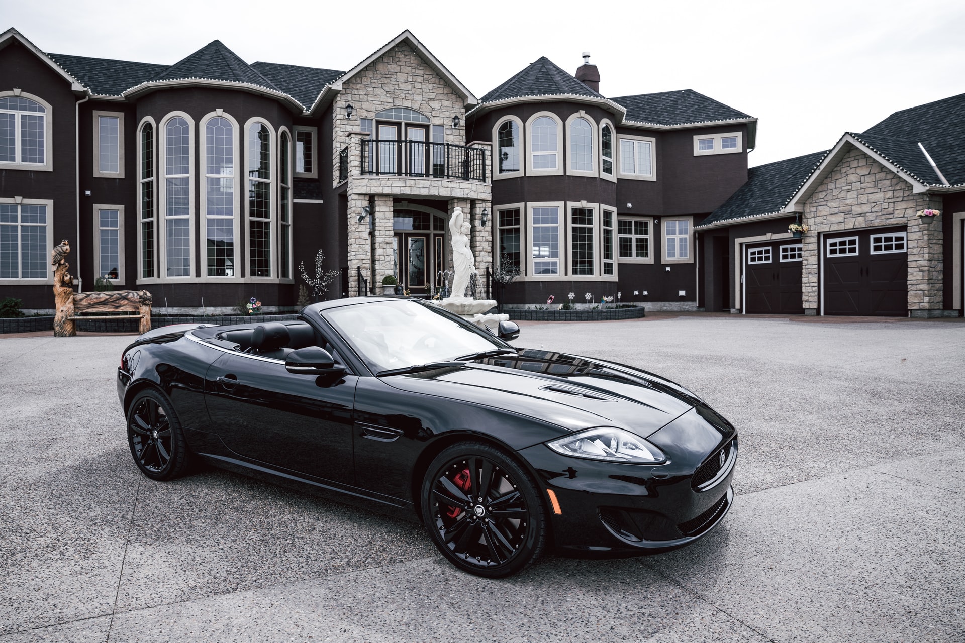 how to manifest money and overcome money blocks - huge mansion with a black sports car parked in the driveway